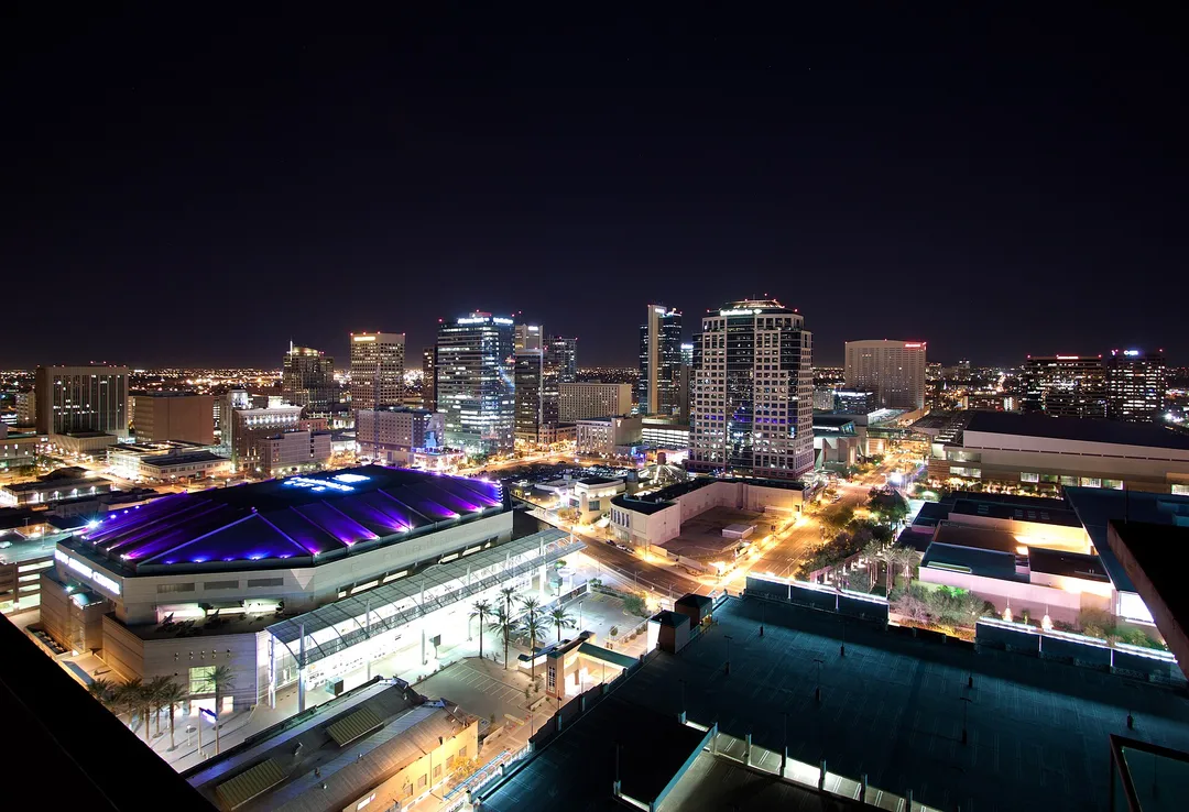 A purple-lit roof among downtown buildings and illuminated streets in Arizona.