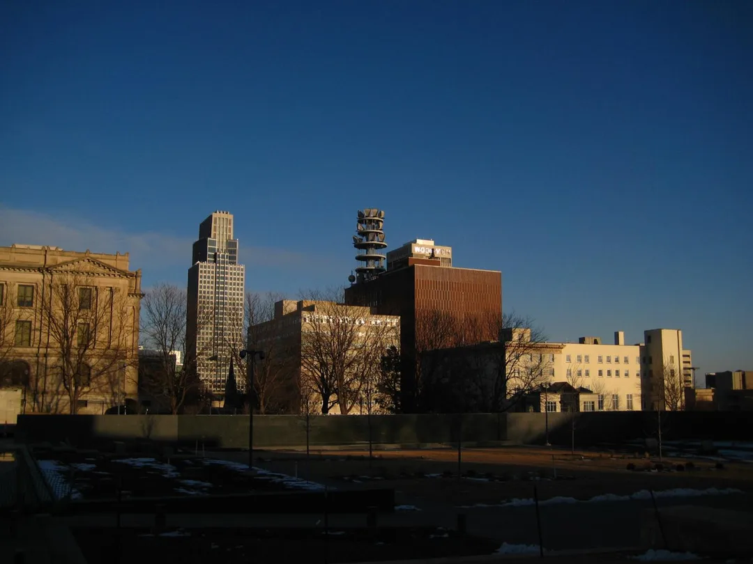 Warm evening light falls on Nebraska office buildings above a row of bare trees.